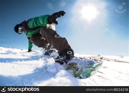 Snowboard freerider in the mountains against sun shine in blue sky.