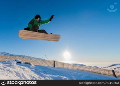 Snowboarder at jump in mountains at sunset sky.