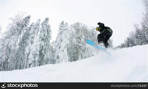Snowboarder doing a jump and free ride on powder snow at winter season