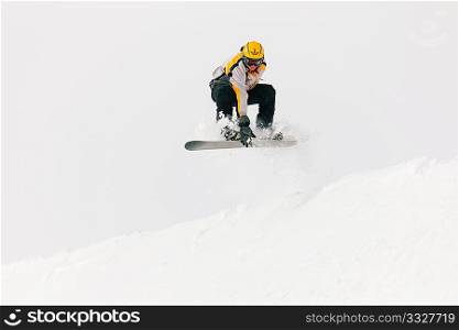 Snowboarder in the alps jumping over an edge of snow grabbing his snowboard