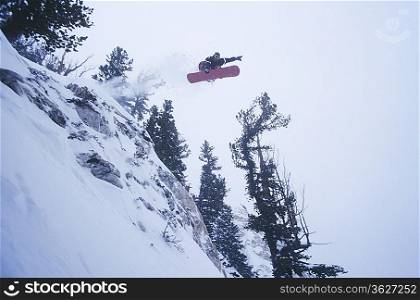 Snowboarder Jumping off Cliff