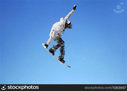 Snowboarder jumping through air with blue sky in background