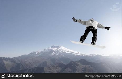 Snowboarder making high jump in clear blue sky. Snowboarding sport