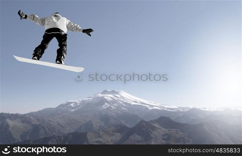 Snowboarder making high jump in clear blue sky. Snowboarding sport