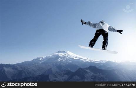 Snowboarder making jump high in clear sky. Snowboarding