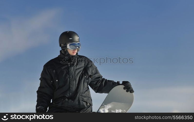 snowboarder relaxing and posing at sunny day on winter season with blue sky in background