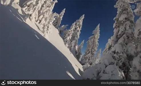Snowboarder rides through deep powder snow in backcountry wilderness