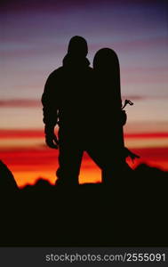 Snowboarder standing outdoors at dusk (silhouette)