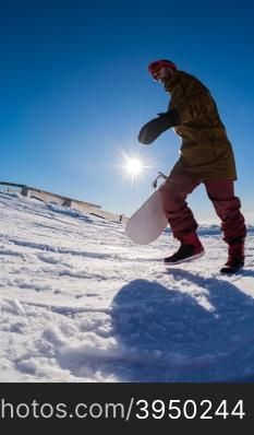 Snowboarder walking through deep fresh snow against blue sky.