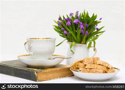snowdrops in a vase, a cup of tea and biscotti on the table