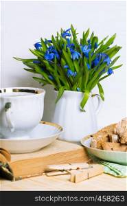 snowdrops in a vase, a cup of tea and biscotti on the table
