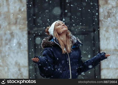 Snowfall. Happy Weekend on a Winter Holidays. Young woman having fun. Snow in the city.. Young Woman on Joyful Winter Day