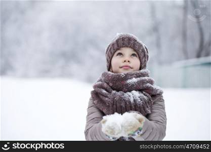 Snowfall, portrait of a happy little girl on the background of a winter park