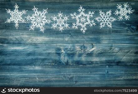 Snowflakes border over rustic wooden background. Winter holidays decoration. Vintage style toned picture