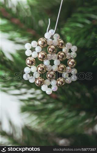 Snowflakes handmade beaded hanging on Christmas tree branches. Close-up. Decorated Christmas tree