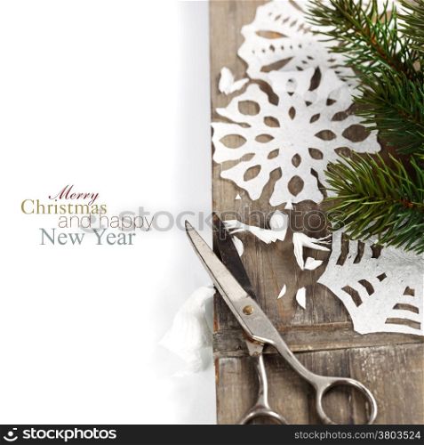 Snowflakes made of paper and christmas tree on wooden background