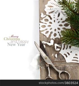 Snowflakes made of paper and christmas tree on wooden background