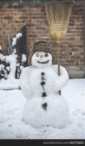 Snowman in the yard holding a broom