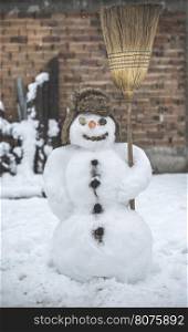 Snowman in the yard holding a broom