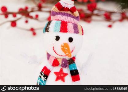 Snowman made of wool over the snow with a branch of red berries background. Christmas decoration