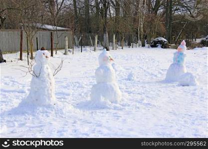 Snowmen built by children. Christmas snowmen made in garden. New Year Attributes. Christmas symbols. A few snowmen in winter. Snowmen built by children. Christmas snowmen made in garden