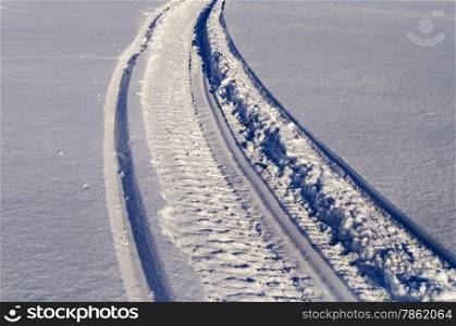 Snowmobile track in snow, sunny winter day