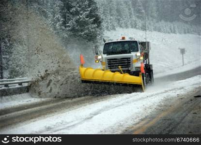 Snowplow clearing road in snowstorm, Rocky Mountains, Idaho