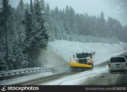 Snowplow clearing road in snowstorm, Rocky Mountains, Idaho