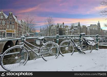 Snowy bicycles in Amsterdam city center the Netherlands at sunset