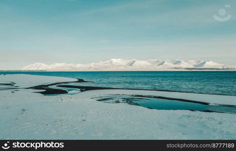 Snowy coast of sea bay landscape photo. Beautiful nature scenery photography with mountain on background. Idyllic scene. High quality picture for wallpaper, travel blog, magazine, article. Snowy coast of sea bay landscape photo