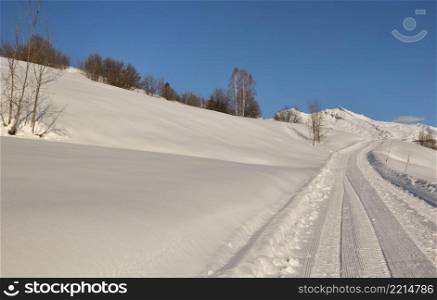 snowy footpath crossing alpine mountain in winter under blue sky. snowy footpath crossing alpine mountain under blue sky