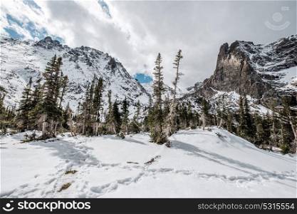 Snowy landscape with rocks and mountains at autumn with cloudy sky. Rocky Mountain National Park in Colorado, USA.