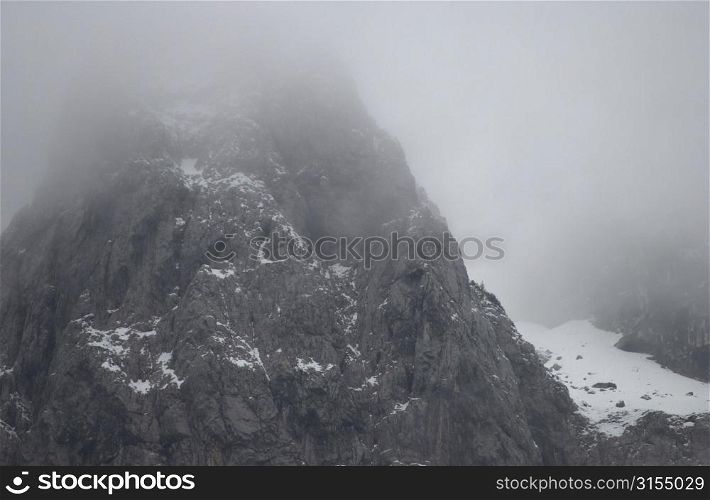 Snowy mountain range surrounded by fog in Slovenia