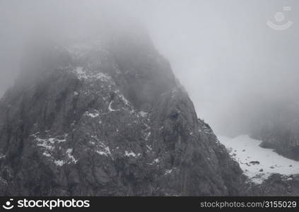 Snowy mountain range surrounded by fog in Slovenia