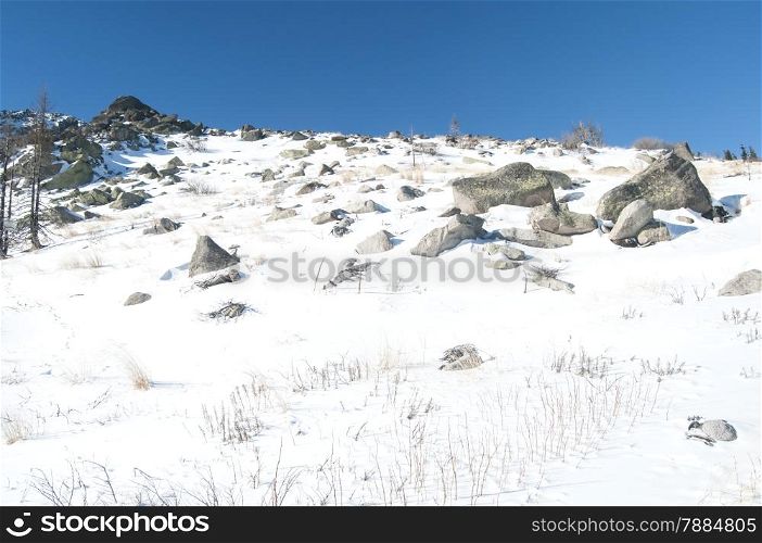 Snowy mountain rock ridge in clear sunny winter day