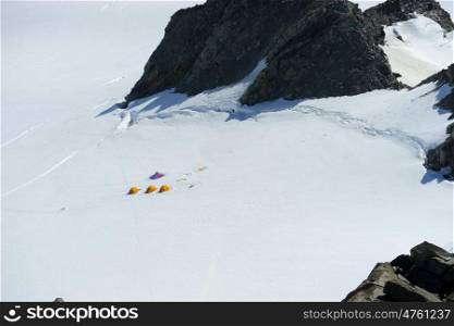 Snowy mountains. Mountain landscape with three tents among snows
