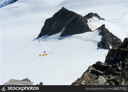 Snowy mountains. Mountain landscape with three tents among snows