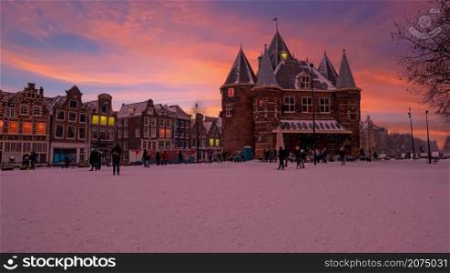Snowy Nieuwmarkt with the Waag building in the city center from Amsterdam in the Netherlands in winter at sunset
