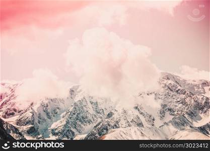 Snowy peaks of the mountain range under the pink sky. Mountain landscape in pastel color.