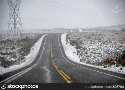 Snowy road in winter without traffic. Focus on snow flakes