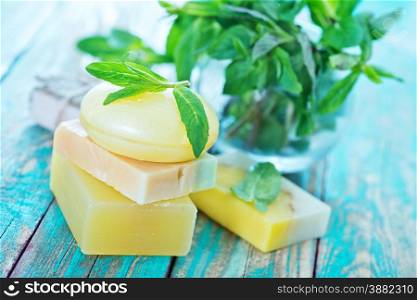 soap and mint leaves on the wooden table