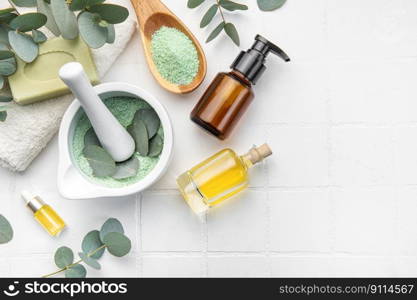 Soap, eucalyptus, towel, massage salt, aroma oil,  spa objects on white tile background. Top view. Skin care, body treatment concept. 