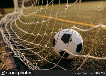 Soccer ball in the gate net, nobody. Football on outdoor stadium, sport game or goal concept