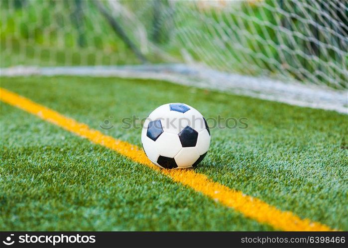Soccer ball on a soccer artificial field with a goal net background. Soccer ball on artificial grass