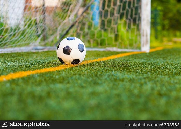 Soccer ball on a soccer artificial field with a goal net background. Soccer ball on artificial grass