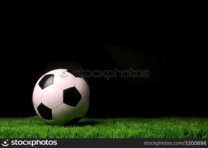 Soccer ball on grass against black