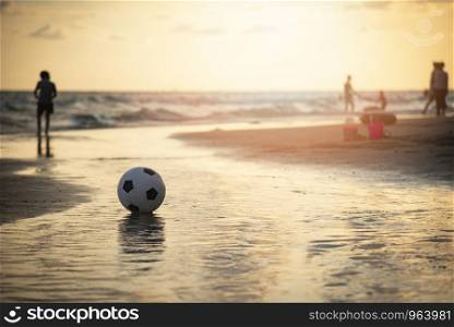 Soccer ball on sand / playing football at the beach sunset sea background