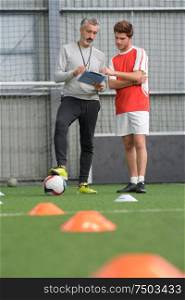 soccer coach and a football player checking the plan