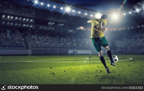 Soccer forward player . Determined football player at stadium hitting ball