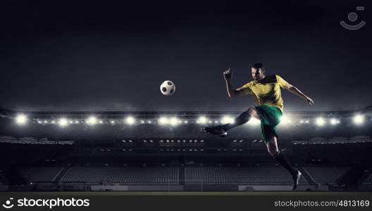 Soccer forward player . Determined football player at stadium hitting ball